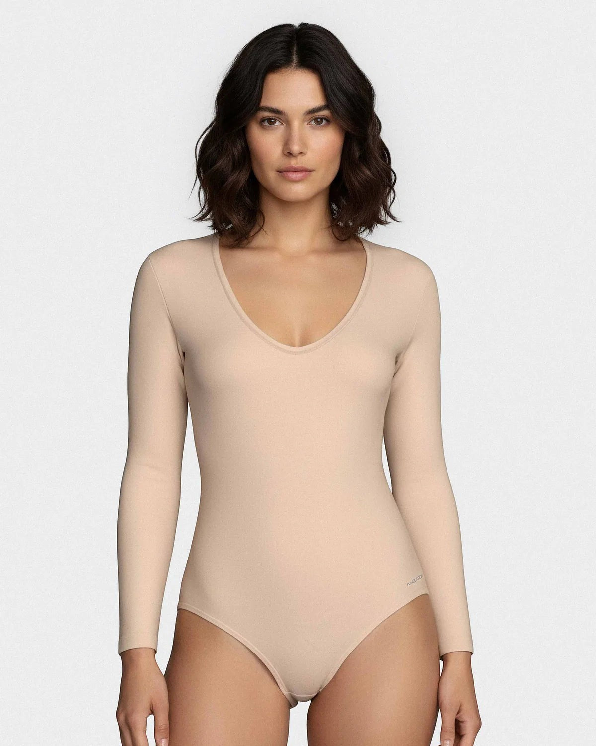 Maison Sarava long sleeve V-neck bodysuit in a soft, seamless beige fabric. Model is wearing a size small.