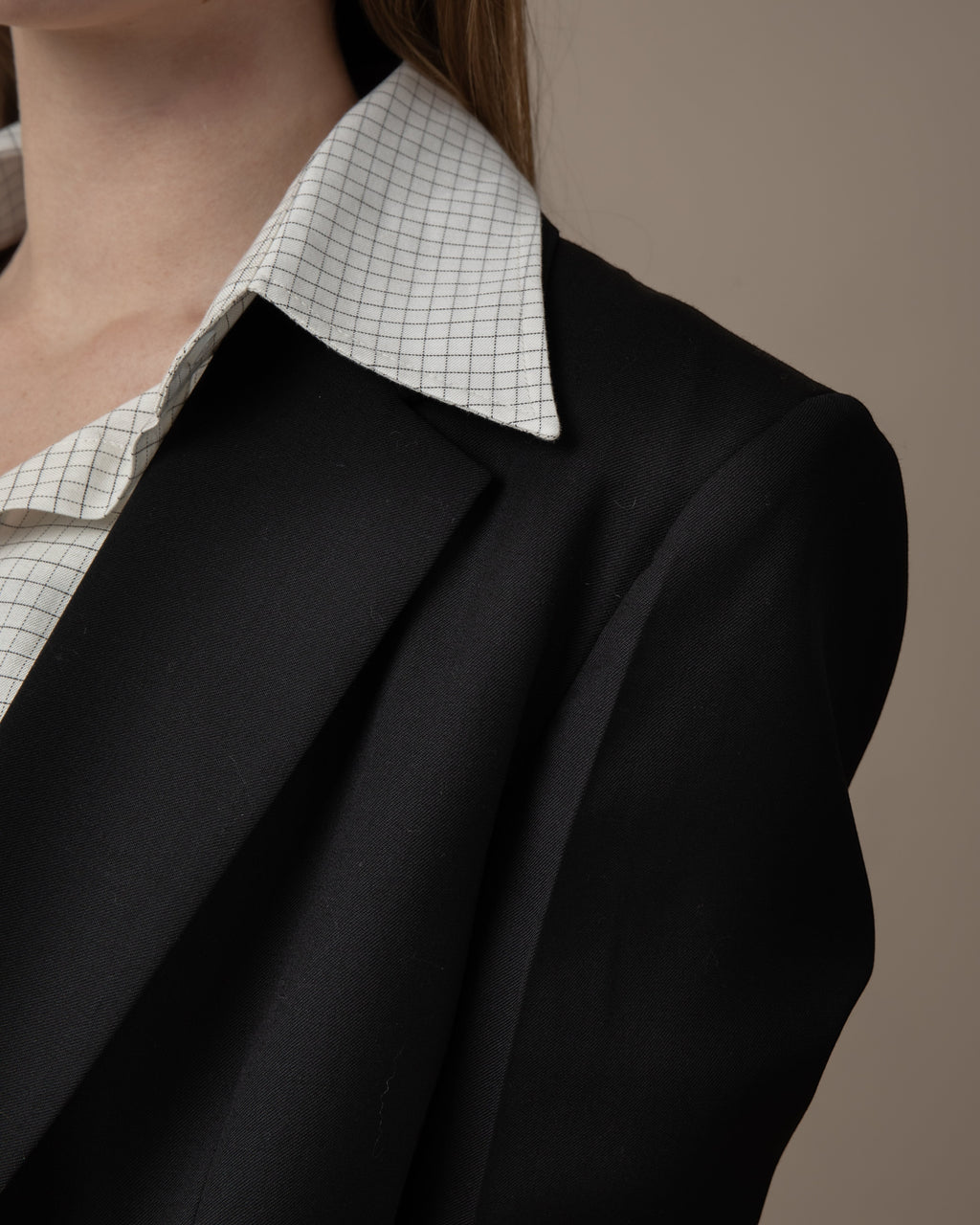 Maison Sarava women's black single-breasted blazer with a white grid-patterned collared shirt underneath.