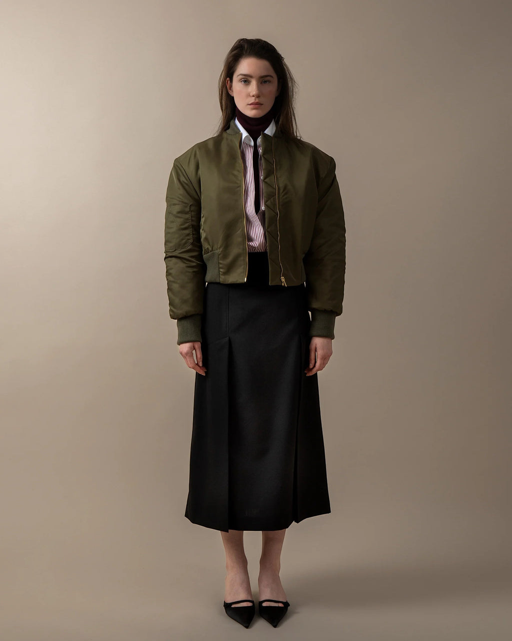 Maison Sarava black straight-fit midi skirt with double front vent and invisible back zip, worn by a model.