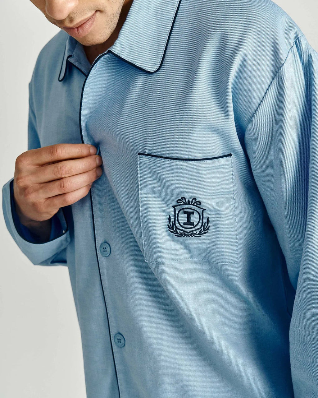 Maison Sarava light blue cotton pajama set with black piping and embroidered crest on pocket. Button-down shirt.