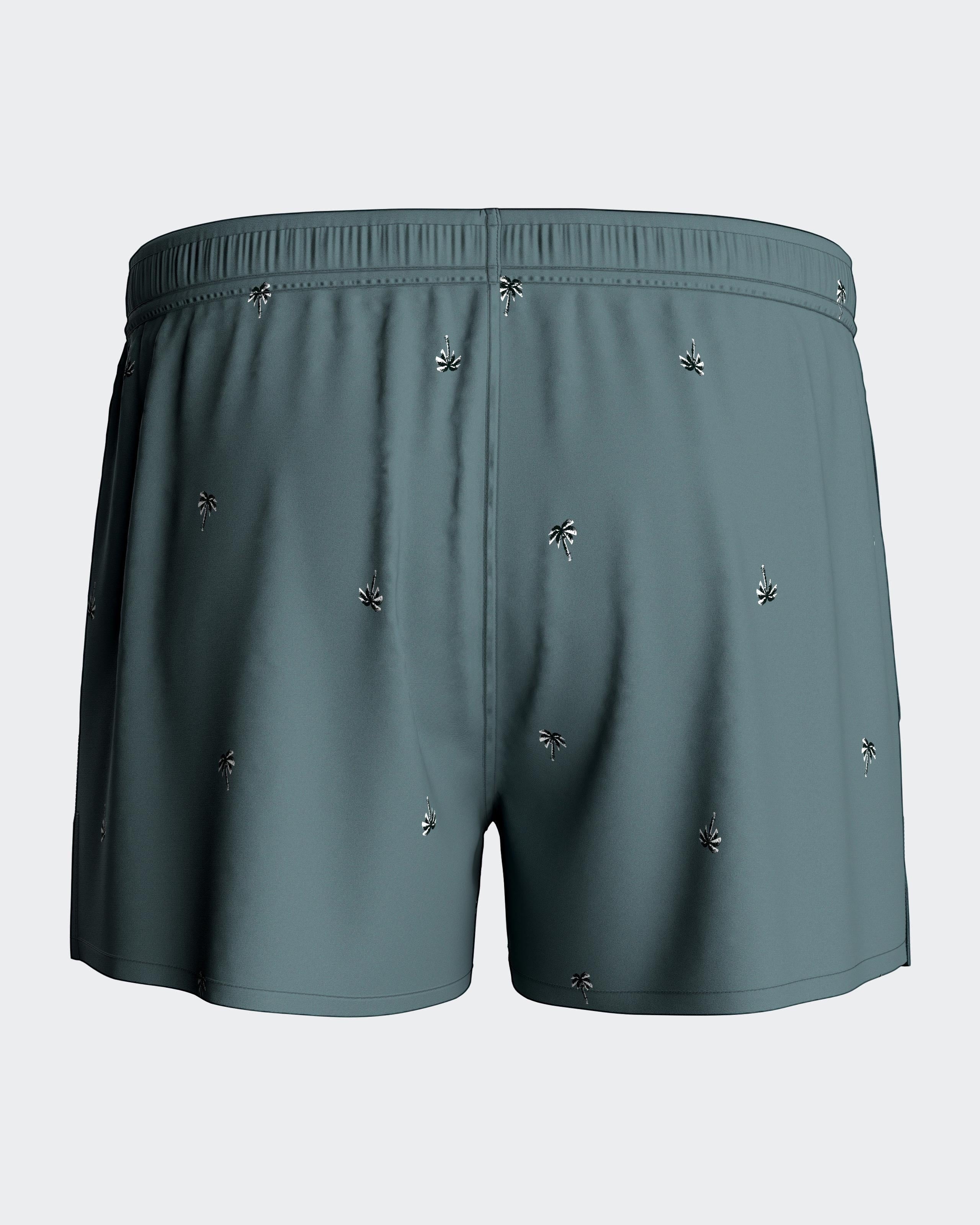 Maison Sarava men's teal swim shorts with a subtle tropical micro-motif and adjustable drawstring.