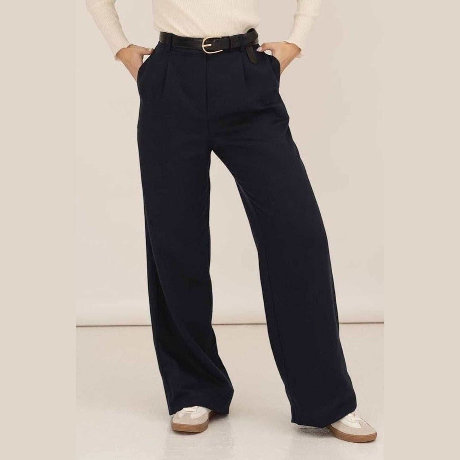Maison Sarava navy wide leg pleated trousers with a black belt and white top, styled with sneakers.