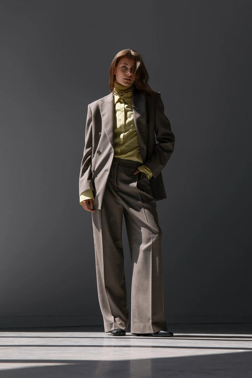 Maison Sarava women's taupe wool double-breasted blazer with peak lapels and flap pockets, paired with matching trousers and a lime green satin shirt.